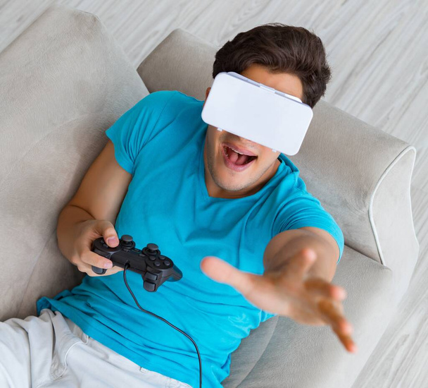 Giovane uomo che indossa occhiali VR rilassante sul divano - Foto, immagini
