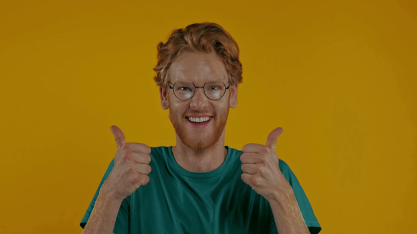 glücklicher rothaariger Mann mit Brille, der vereinzelt Daumen hoch auf gelb zeigt - Filmmaterial, Video