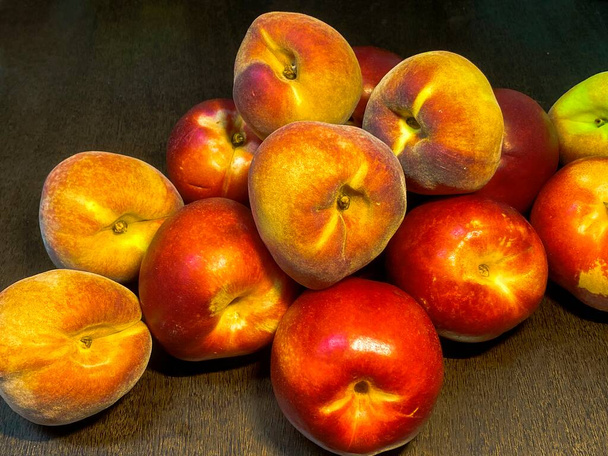 Peaches and Nectarines, a peach of a variety with smooth, thin, brightly colored skin and rich firm flesh, on dark brown wooden table - Photo, Image