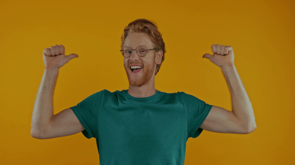 gelukkig roodharige man wijzend naar zichzelf en tonen duimen omhoog geïsoleerd op geel - Video