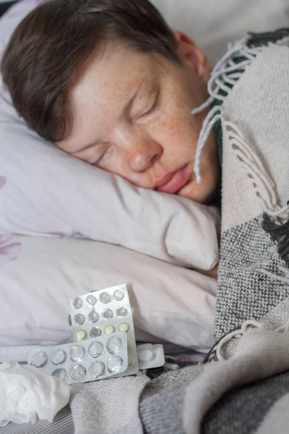 Rijpere brunette vrouw slapen in bed onder ruitdeken, concept van ziekte of kou, behandeling thuis, selectieve focus - Foto, afbeelding