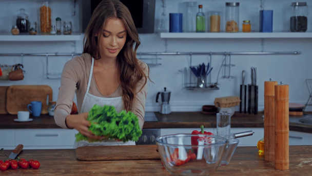 glückliches Mädchen berührt Schüsseln und hält Salat in der Küche  - Filmmaterial, Video