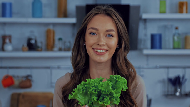 счастливая женщина нюхает свежий салат на кухне  - Кадры, видео