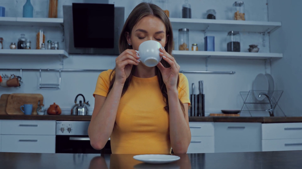 красивая молодая женщина пьет кофе на кухне  - Кадры, видео