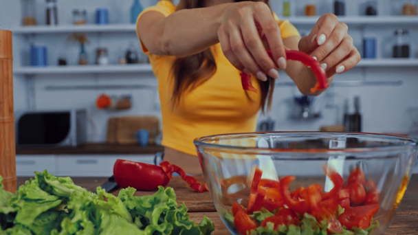vista ritagliata di ragazza mettendo peperone in ciotola con insalata - Filmati, video