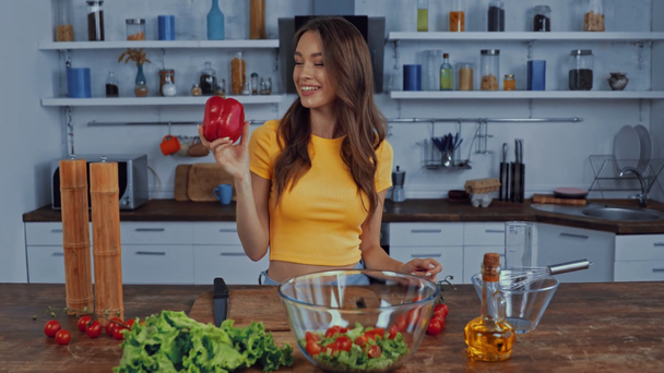happy woman throwing in air bell pepper near ingredients on table - Video, Çekim