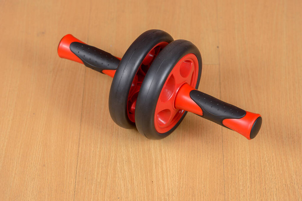 Portrait of ab wheel exercise equipment on wooden floor - Foto, Imagen
