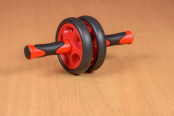 Retrato de un equipo de ejercicios con ruedas abdominales en suelo de madera - Foto, imagen