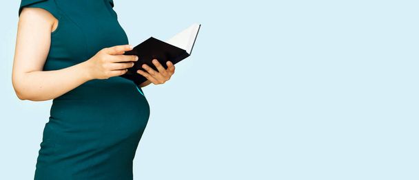 Mulher grávida de pé e livro de leitura
 - Foto, Imagem