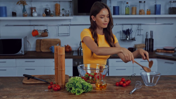 happy woman mixing fresh salad in kitchen  - Filmati, video