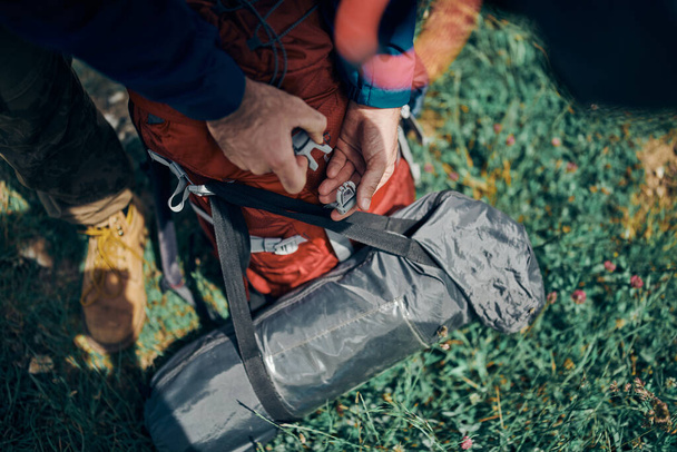 Closeup of man buckling backpack on camping trip. - Foto, afbeelding