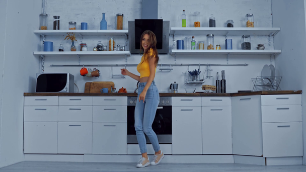 Χαρούμενη γυναίκα χορεύει στη μοντέρνα κουζίνα  - Πλάνα, βίντεο
