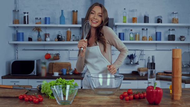 happy woman holding whisk while dancing and singing in kitchen  - Filmagem, Vídeo
