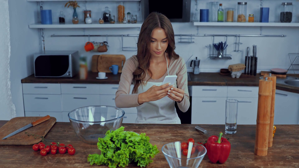 donna attraente scattare foto di verdure in cucina  - Filmati, video