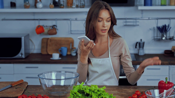 girl using voice assistant while holding smartphone near ingredients  - Filmagem, Vídeo