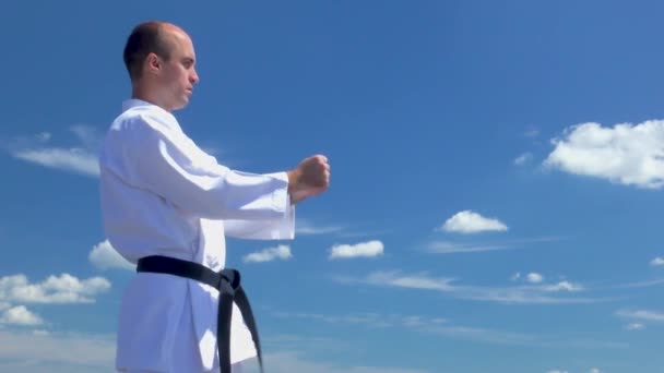 На фоне голубого неба с облаками, спортсмен тренируется ногами - Кадры, видео