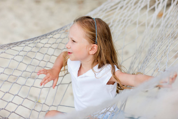 Adorable little girl on summer vacation relaxing in hammock at beach - Fotó, kép