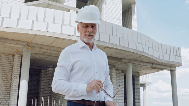 Ingeniero guapo con plano sonriendo en el sitio de construcción
 - Imágenes, Vídeo