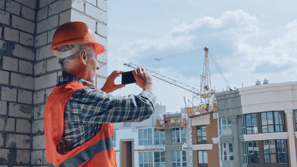 Constructor tomando fotos con teléfono inteligente en el sitio de construcción - Imágenes, Vídeo