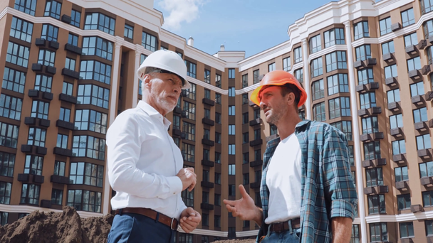 Inżynier i budowniczy rozmawiający podczas spotkania na placu budowy - Materiał filmowy, wideo