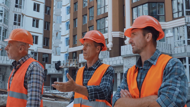Építők digitális táblagéppel és tervrajzzal séta az építési területen - Felvétel, videó