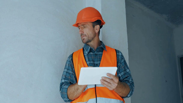Przystojny budowniczy przy użyciu tabletu cyfrowego na placu budowy - Materiał filmowy, wideo