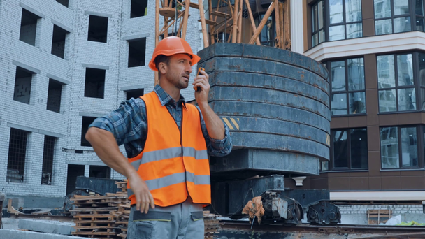 Costruttore gesticolando e utilizzando walkie talkie in cantiere - Filmati, video