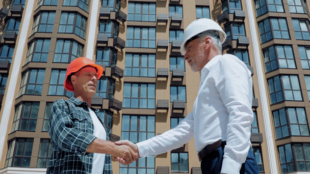 Smiling engineer and builder handshaking on construction site - Footage, Video