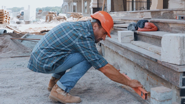 Builder measuring ground with building level on construction site - Video
