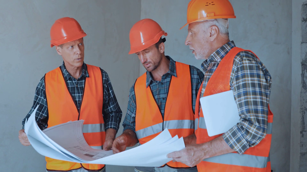 Constructeurs avec tablette numérique regardant les plans sur le chantier de construction - Séquence, vidéo