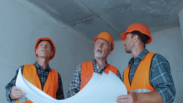 Constructores hablando mientras sostienen planos en el sitio de construcción
 - Imágenes, Vídeo