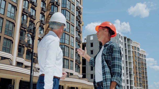 Insinööri ja rakentaja kättelee ja puhuu rakennustyömaalla - Materiaali, video