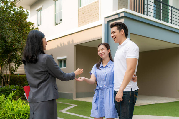 Azji szczęśliwy uśmiech młoda para wziąć klucze nowy duży dom od agenta nieruchomości lub pośrednika nieruchomości przed ich domem po podpisaniu umowy, koncepcja nieruchomości, przeprowadzka do domu lub wynajem nieruchomości - Zdjęcie, obraz