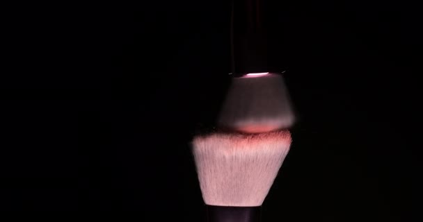 Twee make-up penselen met roze poeder op een donkere achtergrond - Video