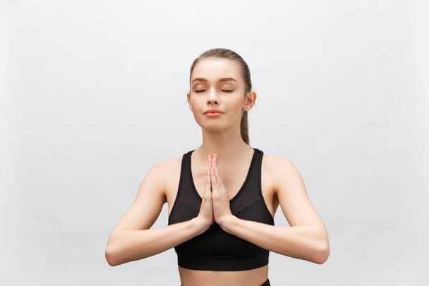 Lotushouding, yoga handen dicht. Yoga vrouw in witte sport kleding meditatie. Jonge vrouw ontspannen en oefenen in witte klasse yoga tegen het raam. Vrijheid. - Foto, afbeelding