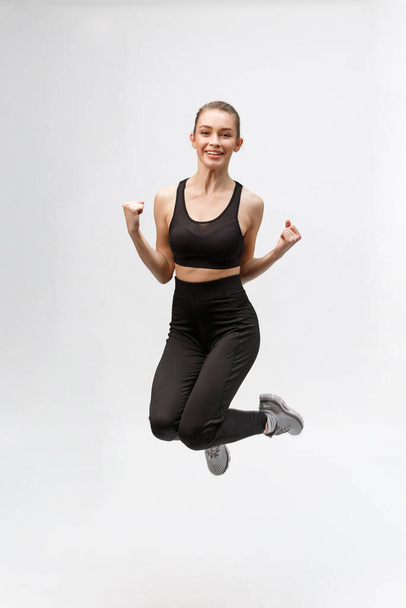 Imagen completa de feliz hermosa mujer fitness sobre fondo gris
 - Foto, Imagen