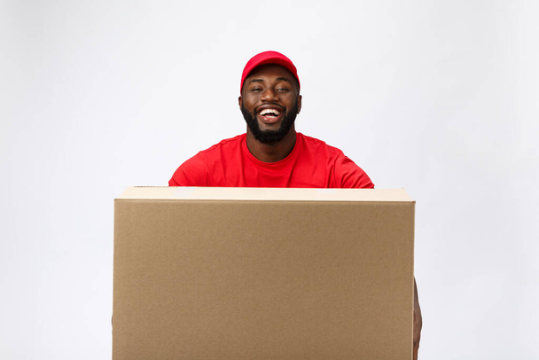 Teslimat Konsepti - Yakışıklı Afro-Amerikalı teslimatçı paket kutusu taşıyor. Grey Stüdyo Arkaplanı 'nda izole edilmiş. Boşluğu Kopyala - Fotoğraf, Görsel