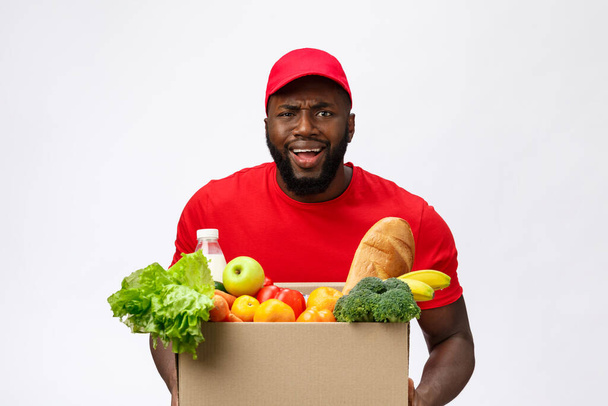 Young african american man holding grocery box in hands with shocking face. Isolated over Grey background. - Photo, Image