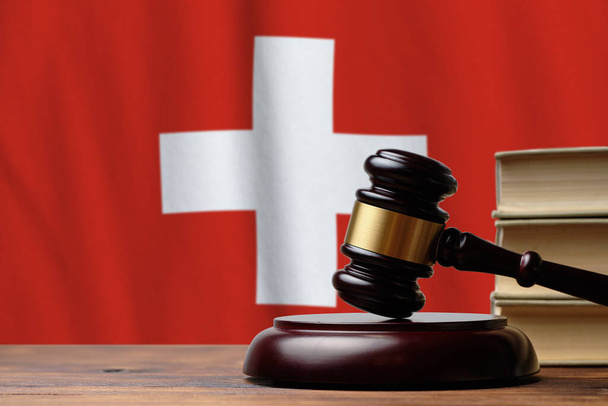 スイス連邦における司法と裁判所の概念。スイスの国旗を背景にハンマー判事. - 写真・画像