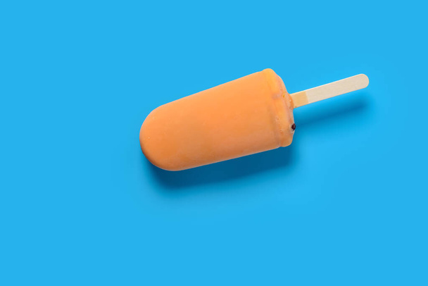 vue du dessus chocolat de couleur orange fraîche popsicle externe avec haricots à l'intérieur sur fond bleu - Photo, image