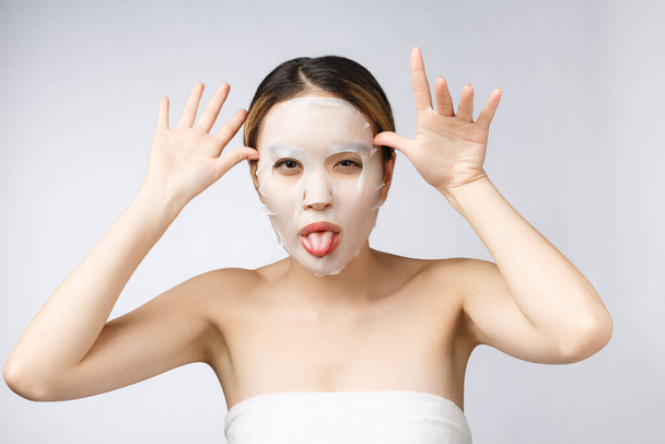 Spa, opieka zdrowotna. Azji dziewczyna z maską kosmetyczną izolat na białym. - Zdjęcie, obraz
