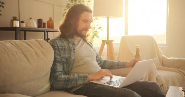Man using laptop and drinking beer at home - Filmagem, Vídeo