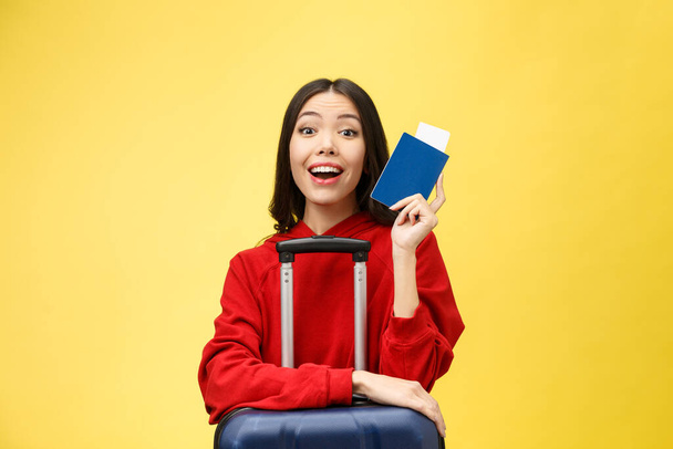 Woman travel. Young beautiful asian woman traveler with passport and suitcase on yellow background - Fotoğraf, Görsel