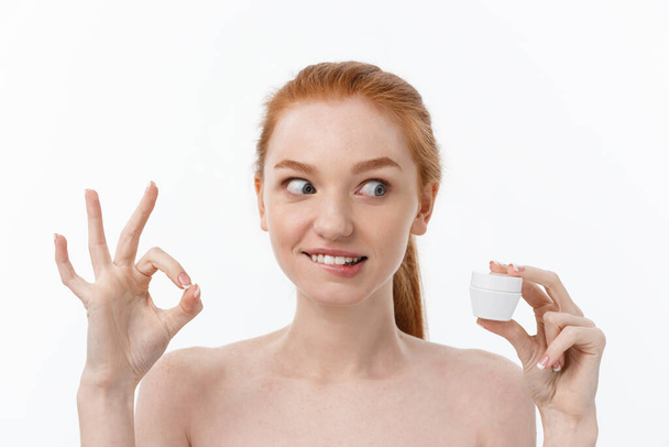 ritratto di bella donna sorridente mentre prende un po 'di crema per il viso isolato su sfondo bianco con spazio copia. - Foto, immagini