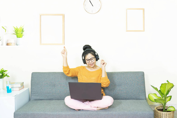 people and leisure concept - happy smiling asian young woman with laptop having fun, resting on weekends at home under quarantine - Fotó, kép