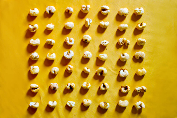 Palomitas de maíz en una cuadrícula en amarillo. Palomitas de maíz dispuestas en una cuadrícula ordenada sobre un fondo amarillo
. - Foto, Imagen