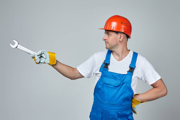 adult man in a construction helmet points with a wrench to the place for the text. concept of construction services - Φωτογραφία, εικόνα