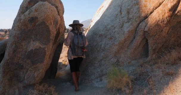Mladá usměvavá žena s batohem je turistika v malebném skalnatém kaňonu při východu slunce - Záběry, video