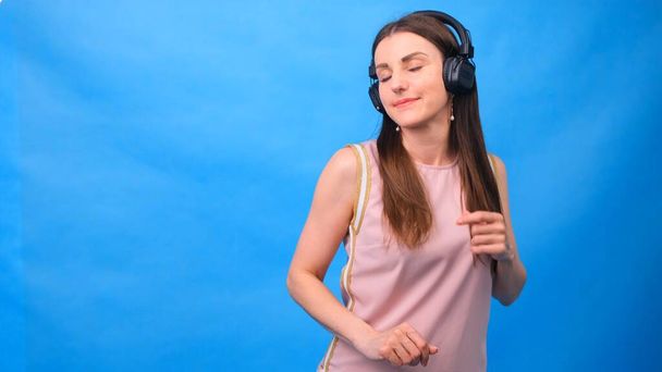 Beautiful Energy Girl with headphones listening to music on a blue background in the studio - Foto, Bild