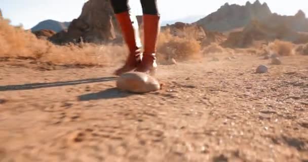 Primer plano de las mujeres independientes en botas rojas senderismo carretera desértica polvorienta al amanecer
 - Metraje, vídeo